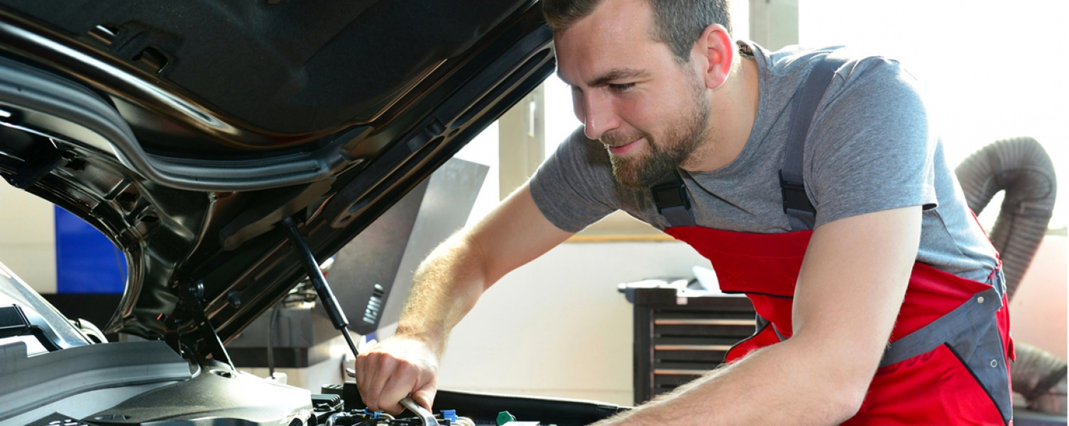 Ein Monteur schraubt in einem Motorraum